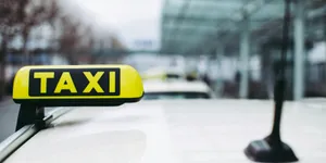 ein Taxi Schild mit einem Flughafen im Hintergrund