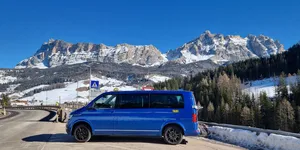 ein VW-Caravelle Taxi vor einer in Schnee bedeckten Bergkette